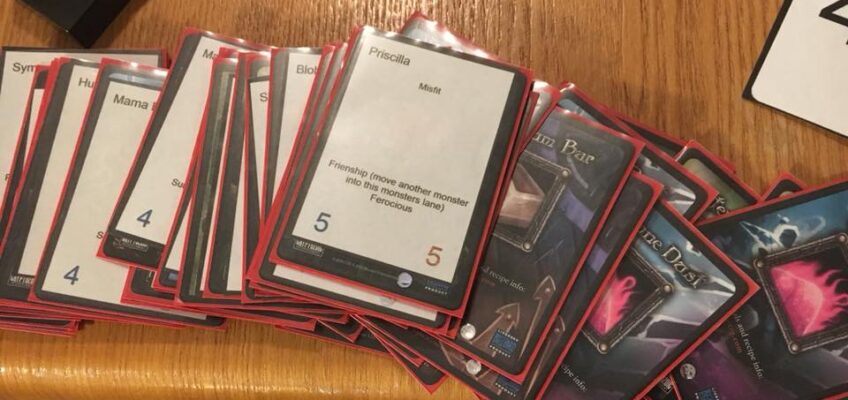 Old sleeved trading cards on the table with newly printed monster cards for Memaws Monsters Tower Defense prototype by Calvin Keene