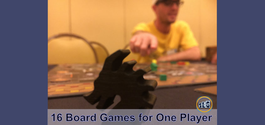Calvin Keeney pointing at a wooden Black Dragon as he plays a fun board game that has a great single player mode for solo board gamers